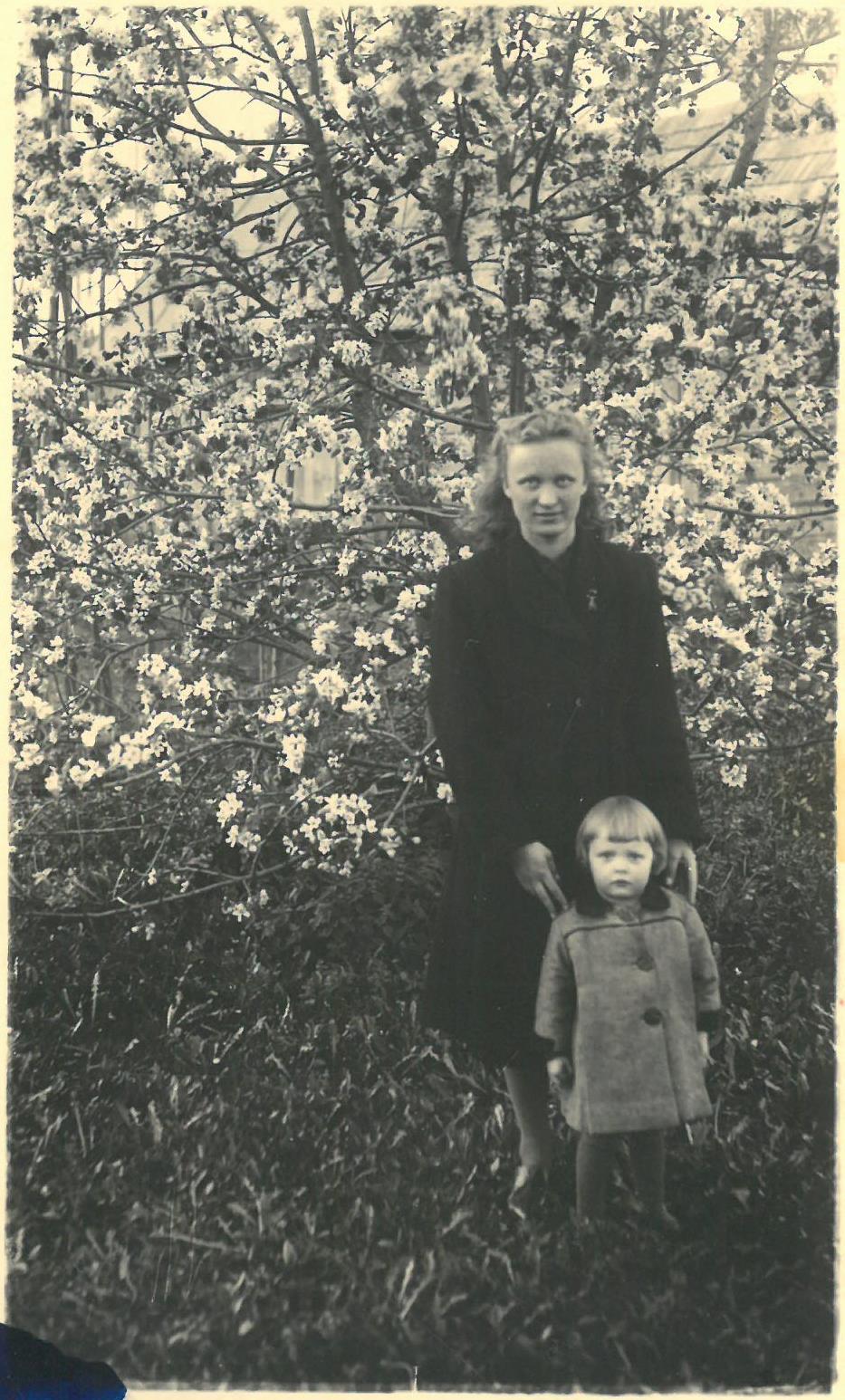 Regina Balčiūnaitė su krikšto mama Genovaite Pečiuliene Rūtų g., Pasvalyje. Kitoje fotografijos pusėje yra Pasvalyje veikusios fotoateljė antspaudas su užrašu: „FOTO / Adamkavičiaus / 1943 VI 2“