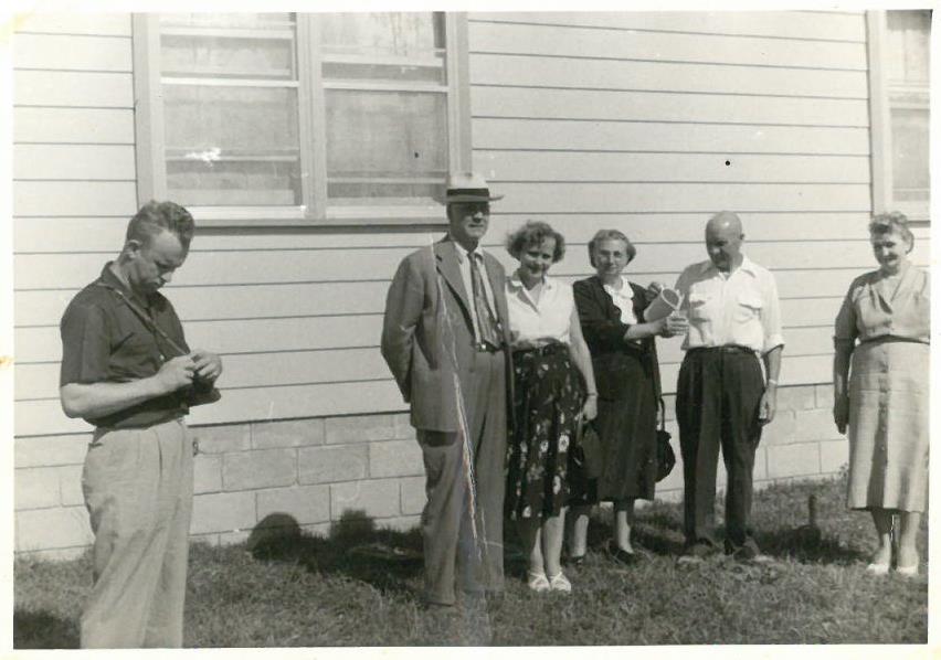 Kazys Balčiūnas su draugais prie savo namų Lemonte, Čikagos priemiestyje, JAV. Kitoje fotografijos pusėje yra užrašas: „Lemont. / liepos mėn. 57.“